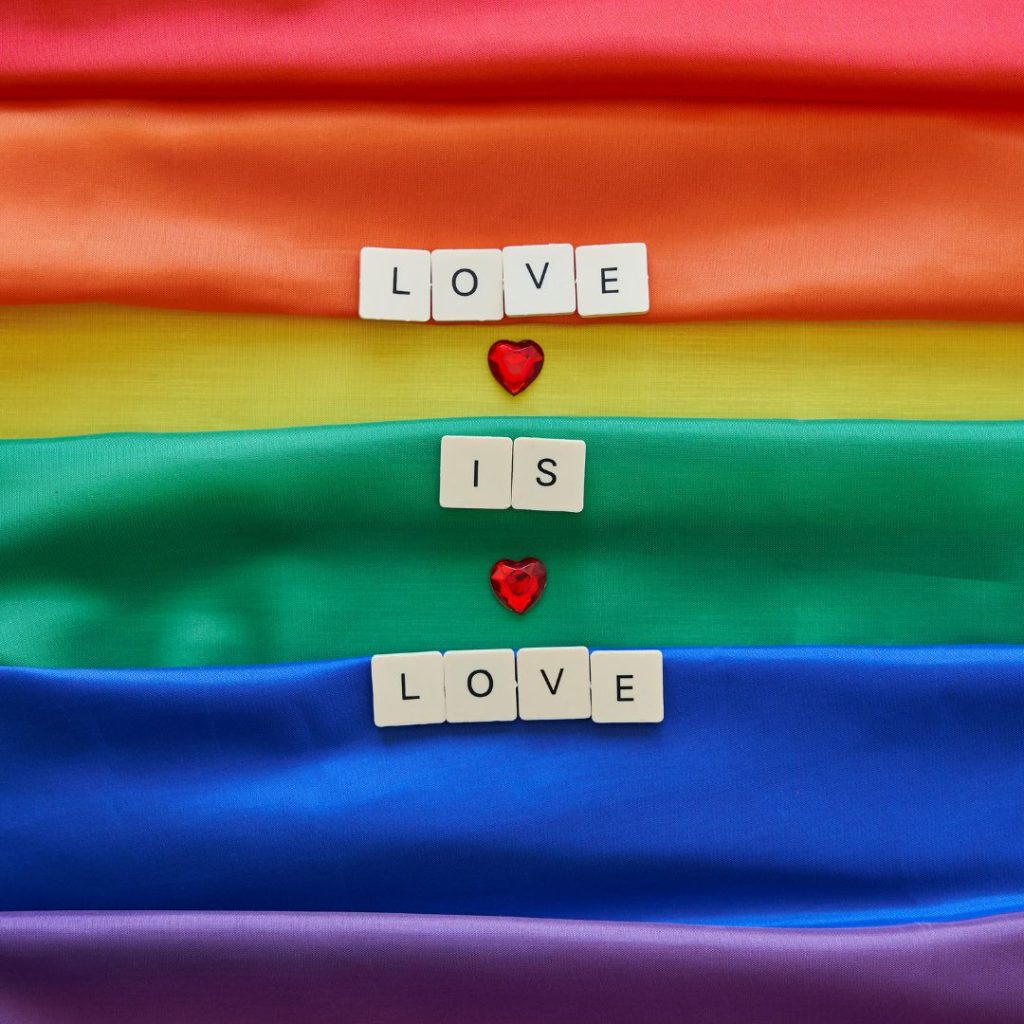 PRIDE flag with scrabble tiles which spell out Love is Love